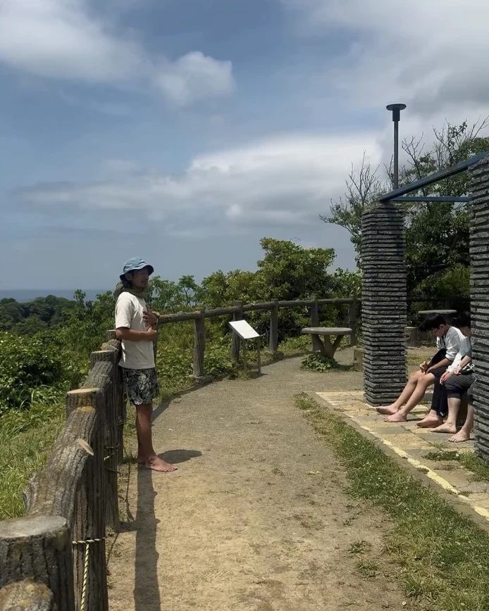 海を望む高台で、裸足の参加者に話をする様子